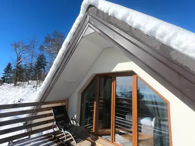a house with a glass door in the snow at Hiša v mesečini - Moonlight house in Cerklje na Gorenjskem