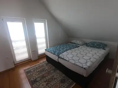 a bedroom with a bed and two windows and a rug at Hiša v mesečini - Moonlight house in Cerklje na Gorenjskem