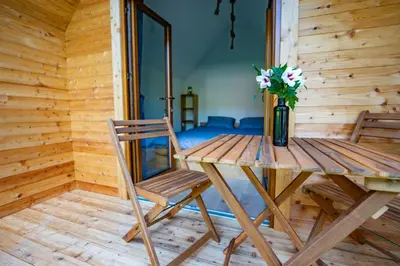 a wooden table with a vase of flowers and a chair at Glamping Logar in Luče