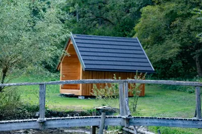a wooden cabin with a black roof and a fence at Glamping Logar in Luče