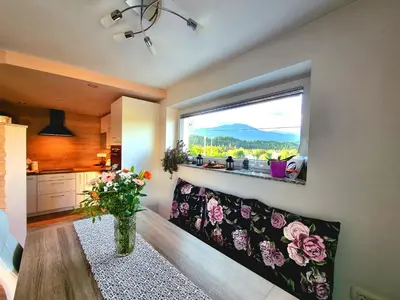 a kitchen with a large window and a vase of flowers at GARTNAR HOME -Hiška s pridihom domačnosti in pogledom na hribe. in Radovljica