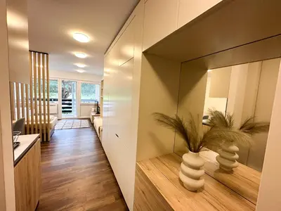 a hallway of a home with a mirror and a living room at Apartma Prisojnik Kranjska Gora in Kranjska Gora