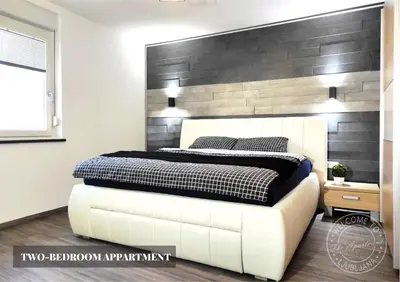a bedroom with a white bed with a wooden headboard at The Apartment - Ljubljana in Ljubljana