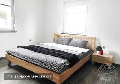 a bedroom with a bed and two windows at The Apartment - Ljubljana in Ljubljana