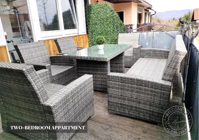a patio with wicker chairs and a table on a deck at The Apartment - Ljubljana in Ljubljana