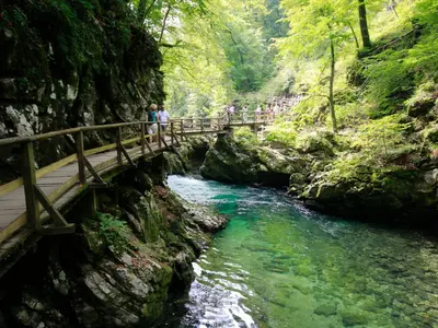 people walking across a bridge over a river at Apartments Apple Garden 4P in Bled