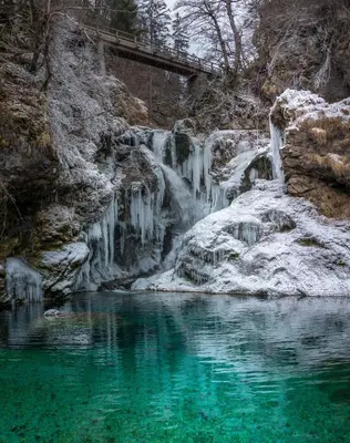 a waterfall with emerald green water and a bridge at Apartments Apple Garden 4P in Bled