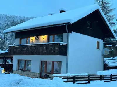 a house covered in snow with a clock on it at Hiša Jezersko in Zgornje Jezersko