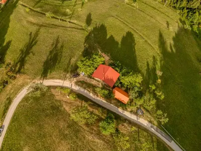 an overhead view of a road in a field with a house at Cottage surrounded by forests - The Sunny Hill in Griže
