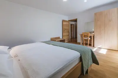 a bedroom with a bed and a dining room at Domačija Log v Bohinju in Bohinjska Bistrica