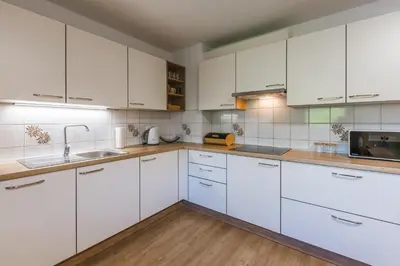 a white kitchen with white cabinets and wooden floors at Domačija Log v Bohinju in Bohinjska Bistrica