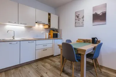 a kitchen with white cabinets and a table and chairs at Domačija Log v Bohinju in Bohinjska Bistrica