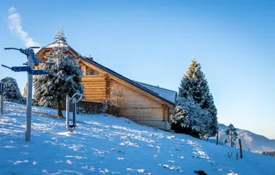 a log cabin in the snow with a sign in front at Brunarica Macesen Smogavc in Zreče