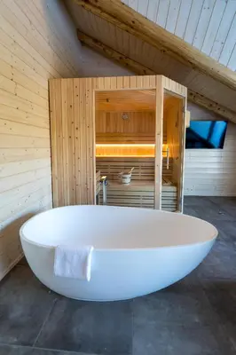 a large white bath tub in a wooden room at Brunarica Macesen Smogavc in Zreče
