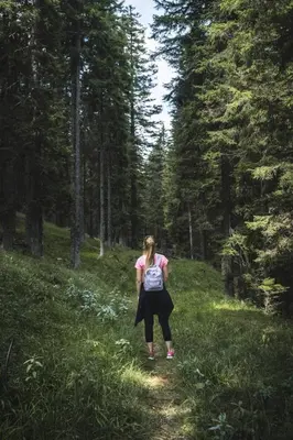 a woman walking on a trail in the woods at Brunarica Macesen Smogavc in Zreče