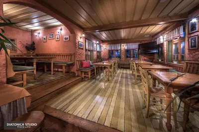 a room with wooden tables and chairs in a restaurant at Brunarica Macesen Smogavc in Zreče