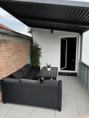 a patio with a couch and a table under awning at NEW GUEST HOUSE 13 in Maribor