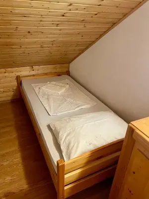 a small bed in a room with a wooden floor at Cosy country home, Lendava in Lendava