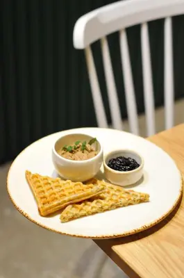a plate of food with waffles and two bowls of dips at Vila De Casa in Ribnica