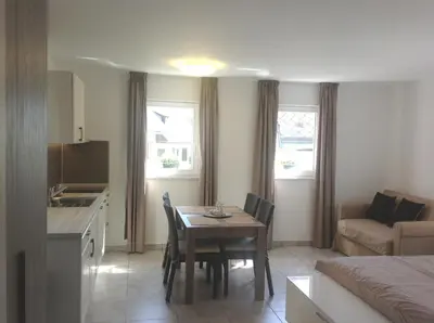 a kitchen and a living room with a table and chairs at Effie Perine Apartments in Bled