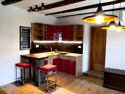 a kitchen with red cabinets and a sink and red stools at Caissa - an old country lady in a new modern dress in Deskle