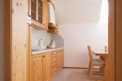 a kitchen with wooden cabinets and a table and a chair at Apartments pr' Špeli in Bohinj