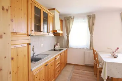 a kitchen with wooden cabinets and a sink and a table at Apartments pr' Špeli in Bohinj