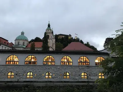 a building with lit windows in front of a city at TAMLiving Ljubljana 2BR Center 3 Bridges Great View Kitchen in Ljubljana