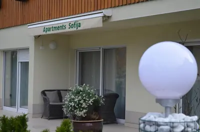 a building with a chair and flowers in front of it at Apartments Sofija in Bled