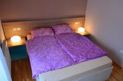 a purple bed in a small room with two lights at Apartments Sofija in Bled