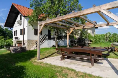 a picnic table under a wooden pergola in a yard at Andy's Holiday Home with HotTub & Sauna in Podbočje