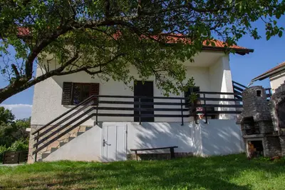 a white house with a staircase and a tree at Andy's Holiday Home with HotTub & Sauna in Podbočje