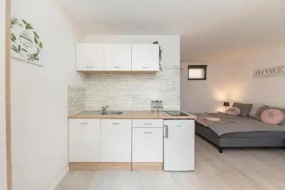 a kitchen with white cabinets and a bed in a room at Apartments Berni in Ljubljana