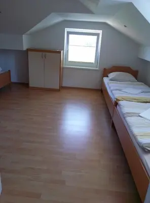 a large room with two beds and a window at Bed and Breakfast Špelca in Pivka