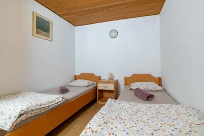 two twin beds in a room with white walls at Bed and Breakfast Špelca in Pivka