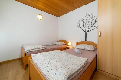 two beds in a room with a tree on the wall at Bed and Breakfast Špelca in Pivka
