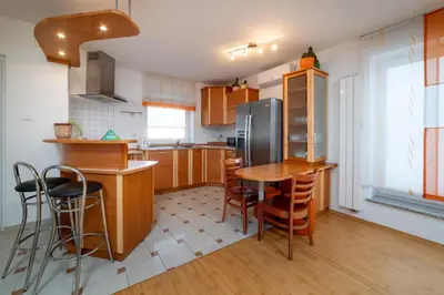 a kitchen with wooden cabinets and a table and chairs at Bed and Breakfast Špelca in Pivka
