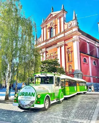 a green and white bus parked in front of a building at Central Ljubljana Apartment , 150m from Prešeren Square in Ljubljana