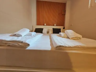 two beds in a room with white sheets and pillows at Central Ljubljana Apartment , 150m from Prešeren Square in Ljubljana
