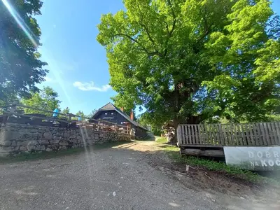 a water fountain in front of a stone fence and a house at koča na pikovem in Črna na Koroškem