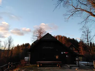 a black barn with a bench in front of it at koča na pikovem in Črna na Koroškem
