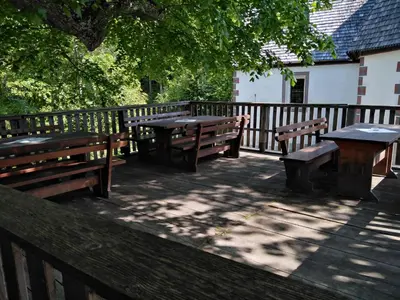 three picnic tables and benches on a wooden deck at koča na pikovem in Črna na Koroškem