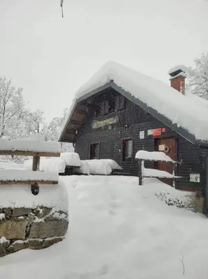 a log cabin with snow on the roof at koča na pikovem in Črna na Koroškem