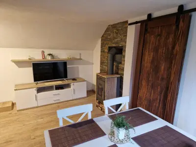 a living room with a dining table and a television at koča na pikovem in Črna na Koroškem