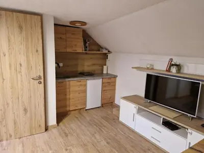 a room with a kitchen with a tv and a door at koča na pikovem in Črna na Koroškem
