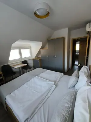 a bedroom with two white beds and a table at Guesthouse Haler in Podčetrtek