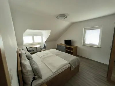 a bedroom with a bed and a desk and two chairs at Guesthouse Haler in Podčetrtek