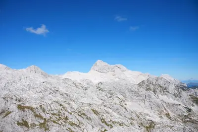 a snow covered mountain with a blue sky in the background at Apartments Sušnik in Bohinj