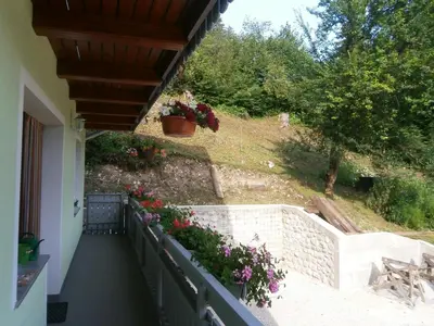 a balcony of a house with flowers in a yard at Apartment Žvan in Bohinj