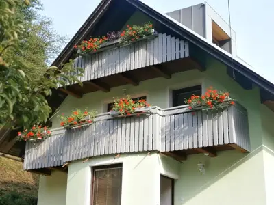 a house with balconies with geraniums on it at Apartment Žvan in Bohinj